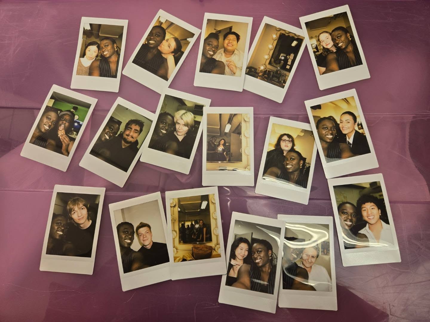 A collection of cast and crew Polaroid photographs spread across purple fabric