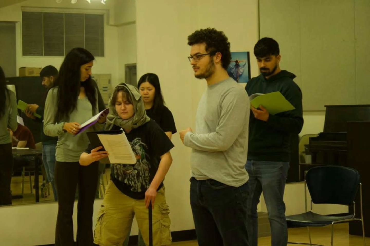 An ensemble working through a scene with scripts in a rehearsal room