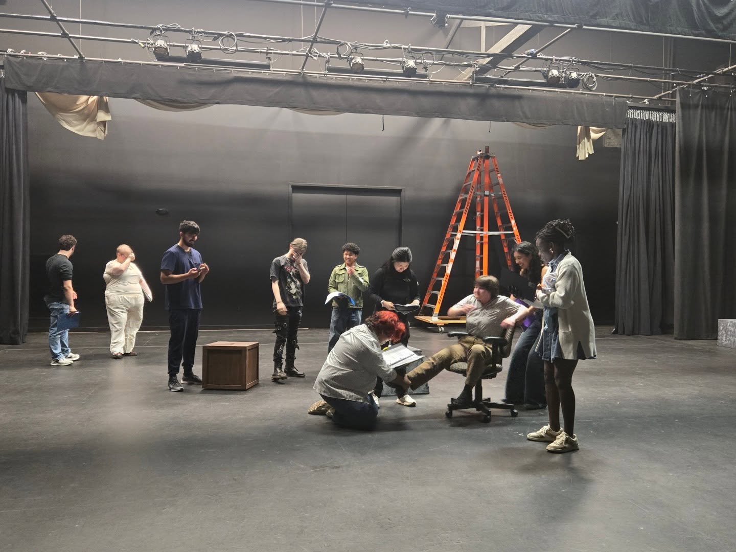 An ensemble rehearsing with scripts on an unfinished stage