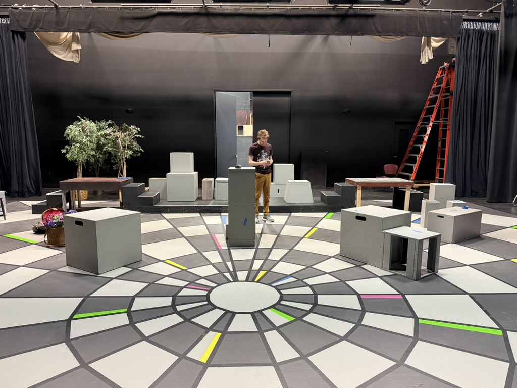 Unpainted set pieces arranged across the geometric stage floor